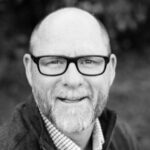 black and white portrait of a man with a bald head and wearing glasses.